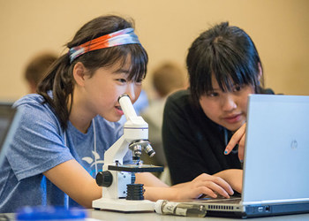 students working working with microscope and laptop